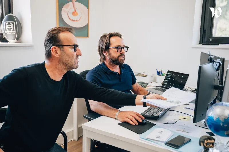 <p>deux hommes qui discutent en regardant un ordinateur</p>
