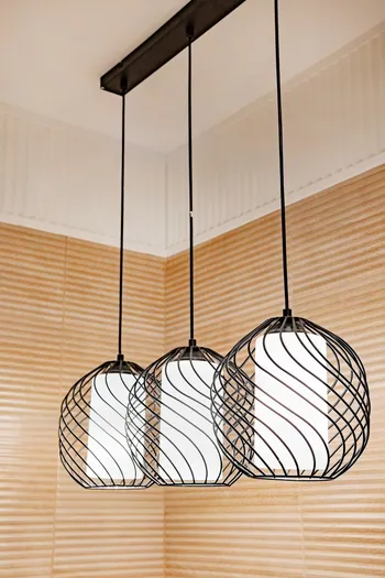 A round lamp with a rectangular iron frame suspended from the ceiling, illuminating in gold. Interior concept.