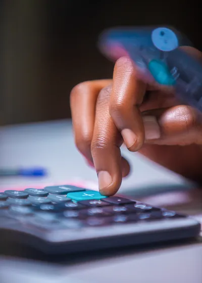 close-up Virtical photo of brown Dark skinned African person hand fingers punching pressing calculator on white table desk close-up Virtical photo of brown Dark skinned African person hand fingers punching pressing calculator on white table desk